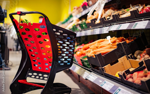 A shopping cart with grocery products in a supermarket photo