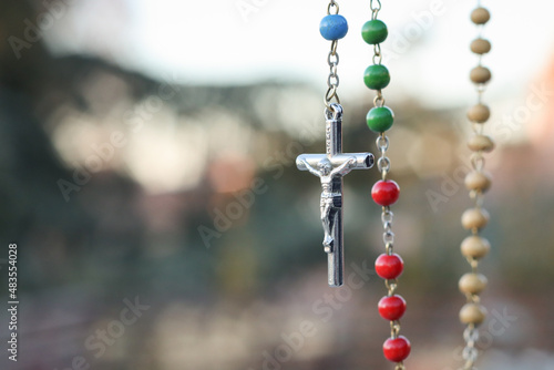 Primer plano de un rosario de colores de la Virgen de Fátima con una cruz plateada. Rosario de los continentes.