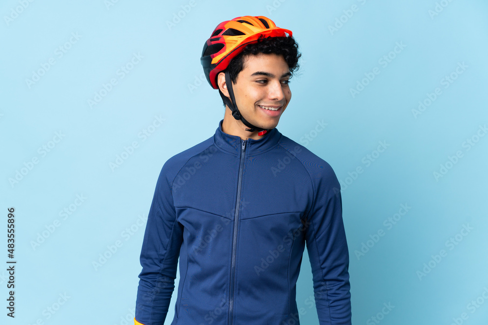 Venezuelan cyclist man isolated on blue background looking to the side and smiling - obrazy, fototapety, plakaty 