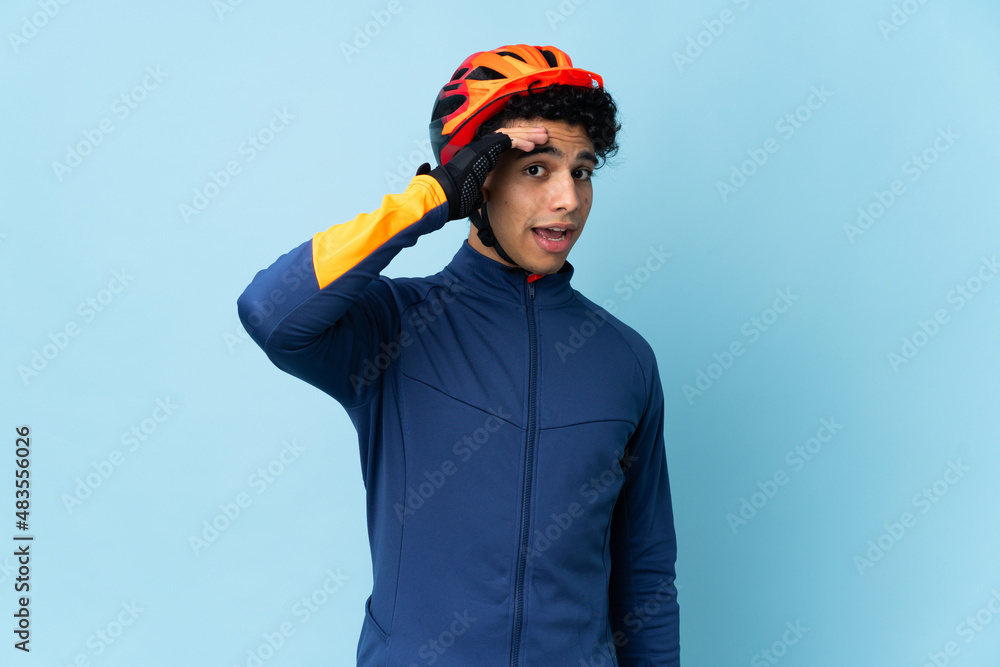 Venezuelan cyclist man isolated on blue background doing surprise gesture while looking to the side Venezuelan cyclist man isolated on blue background doing surprise gesture while looking to the side