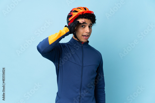 Venezuelan cyclist man isolated on blue background doing surprise gesture while looking to the side © luismolinero