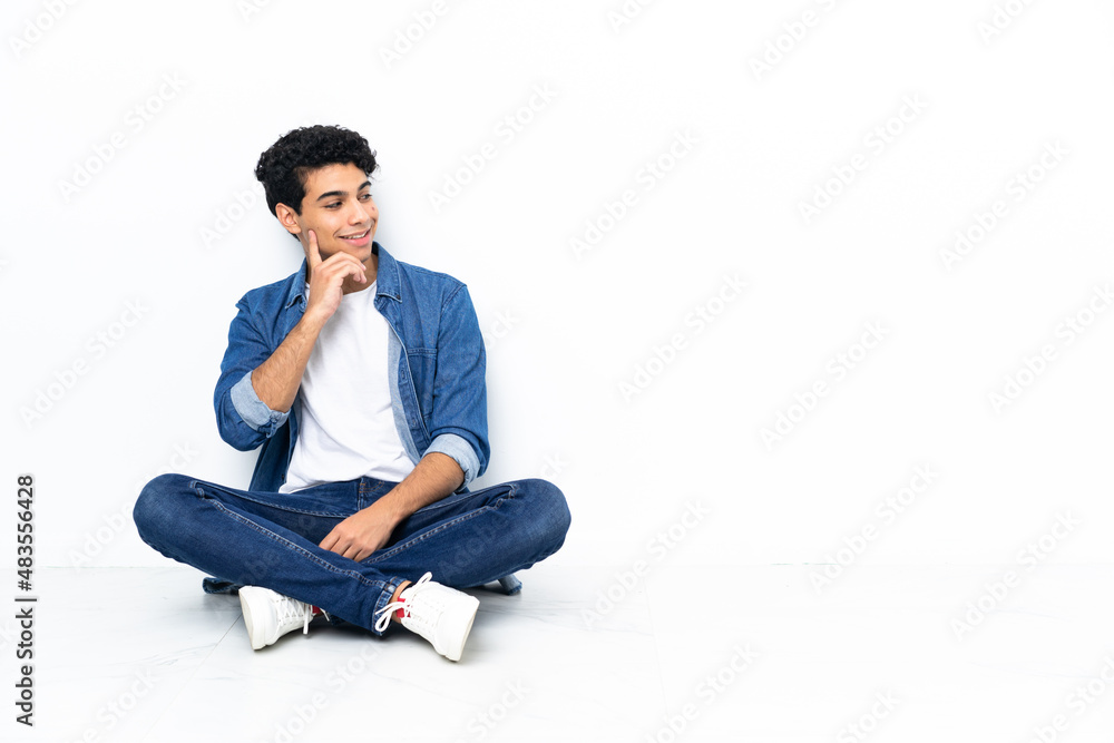 Venezuelan man sitting on the floor thinking an idea while looking up Venezuelan man sitting on the floor thinking an idea while looking up