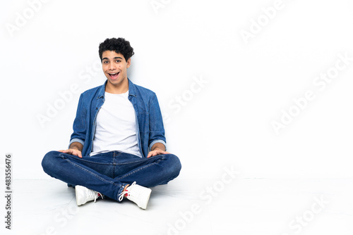 Venezuelan man sitting on the floor with surprise facial expression © luismolinero