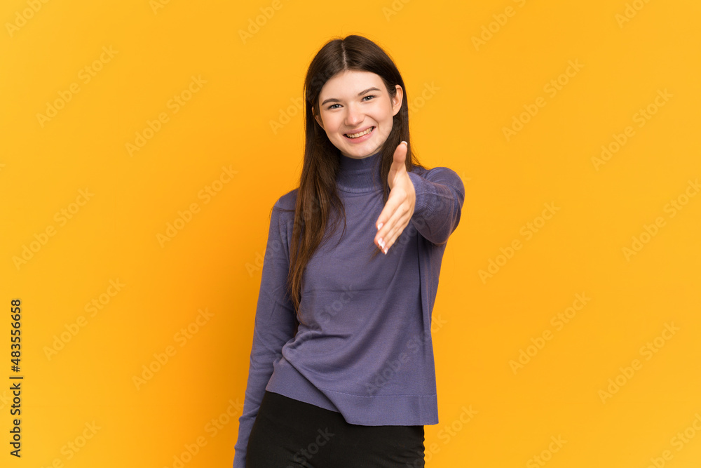Young Ukrainian girl isolated on yellow background shaking hands for closing a good deal Young Ukrainian girl isolated on yellow background shaking hands for closing a good deal