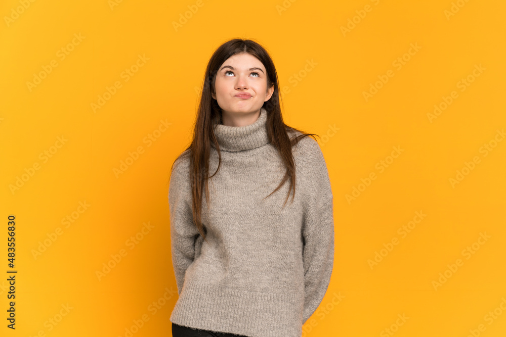 Fototapeta premium Young Ukrainian girl isolated on yellow background and looking up