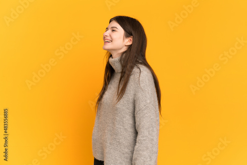 Young Ukrainian girl isolated on yellow background laughing in lateral position © luismolinero