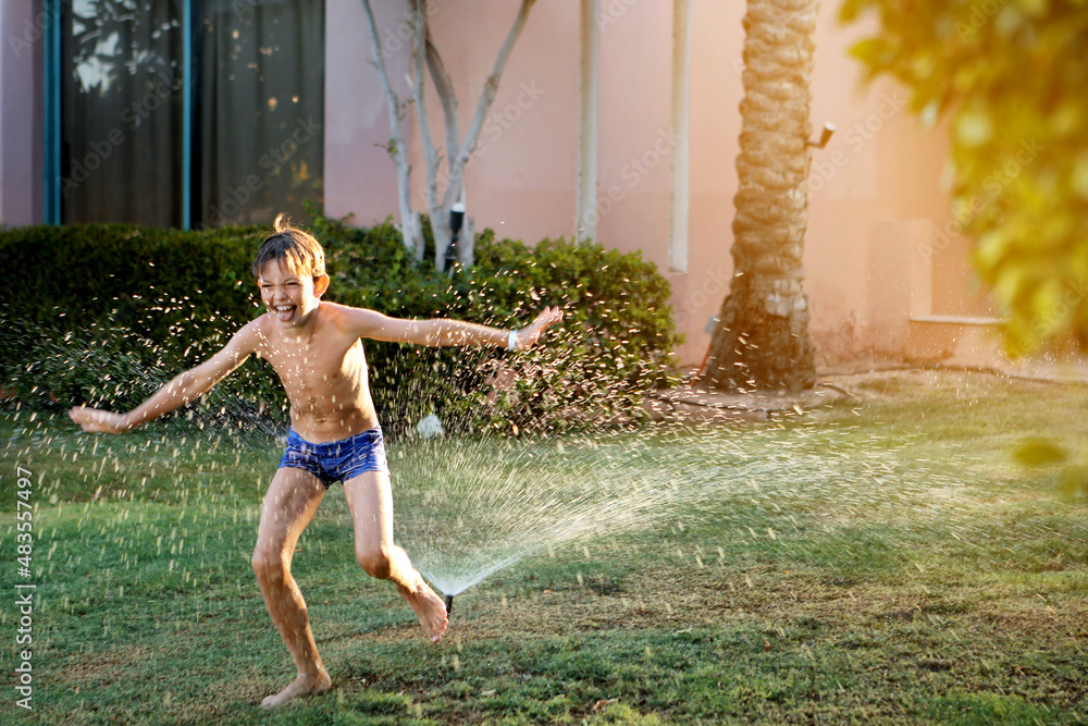 Obraz premium summer. a cheerful boy in the shops jumps under a water fountain