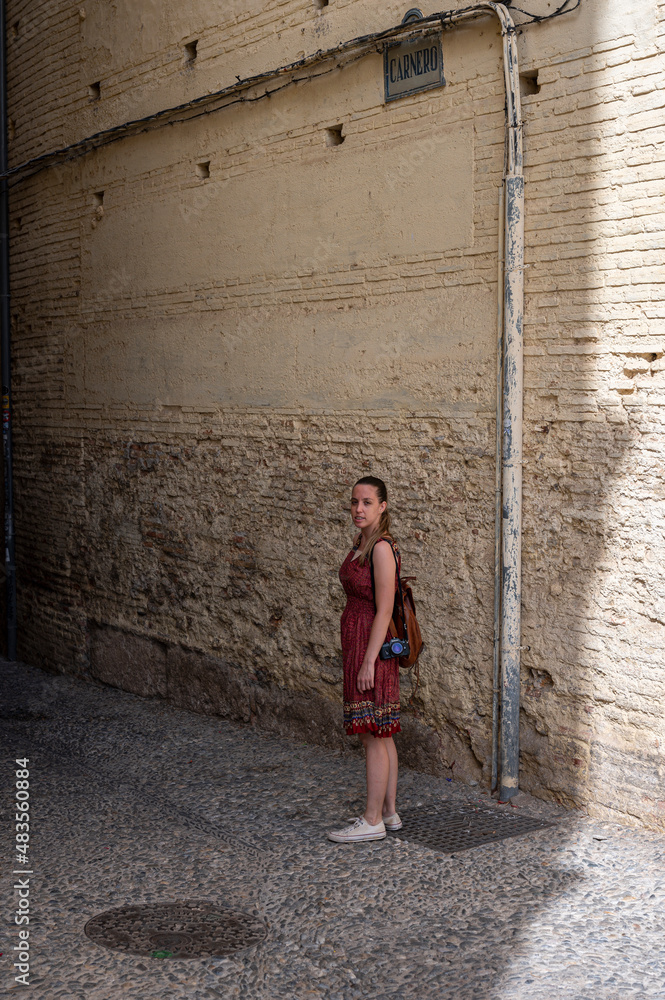 Traveler young girl in red dress in old alley