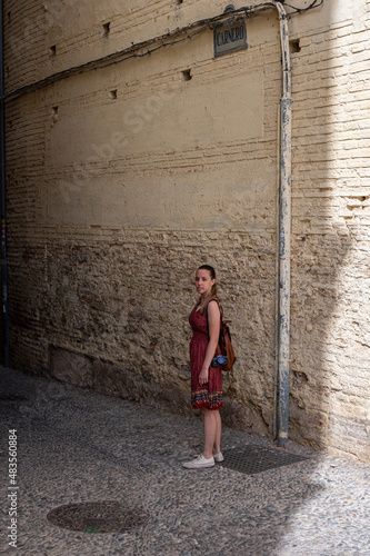 Traveler young girl in red dress in old alley