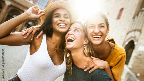 Three young multiracial women having fun on city street outdoors - Mixed race female friends enjoying a holiday day out together - Happy lifestyle, youth and young females concept