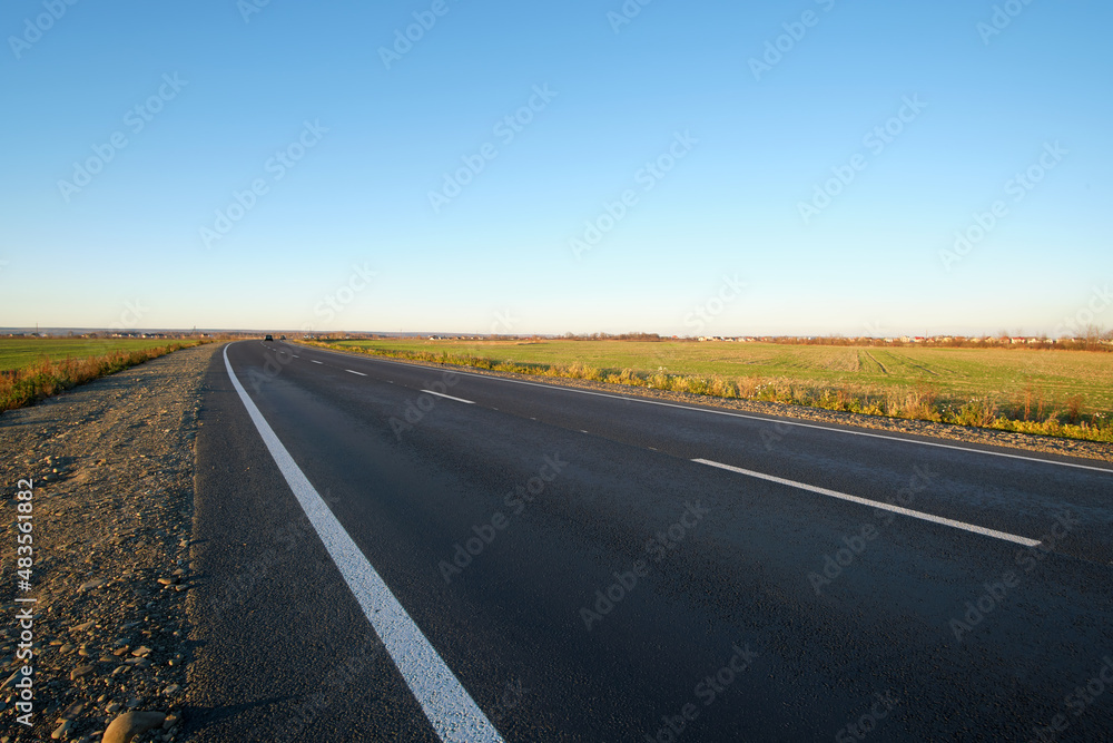 Empty intercity road with asphalt surface and white markings in evening