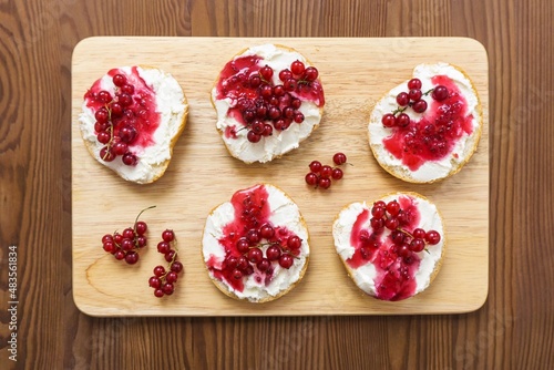 Healthy breakfast, toasts with curd cheese, berry jam and red currant berries, diet food, on a wooden background, selective focus, top view.
