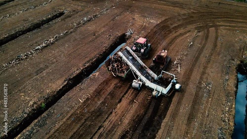 Peat Harvester Tractor on Collecting Extracting Peat. Mining and harvesting peatland. Area drained of the mire are used for peat extraction. Drainage and destruction of peat bogs.  photo