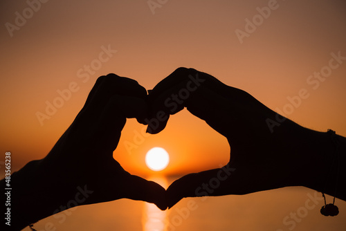 hands in the form of a heart at sunset