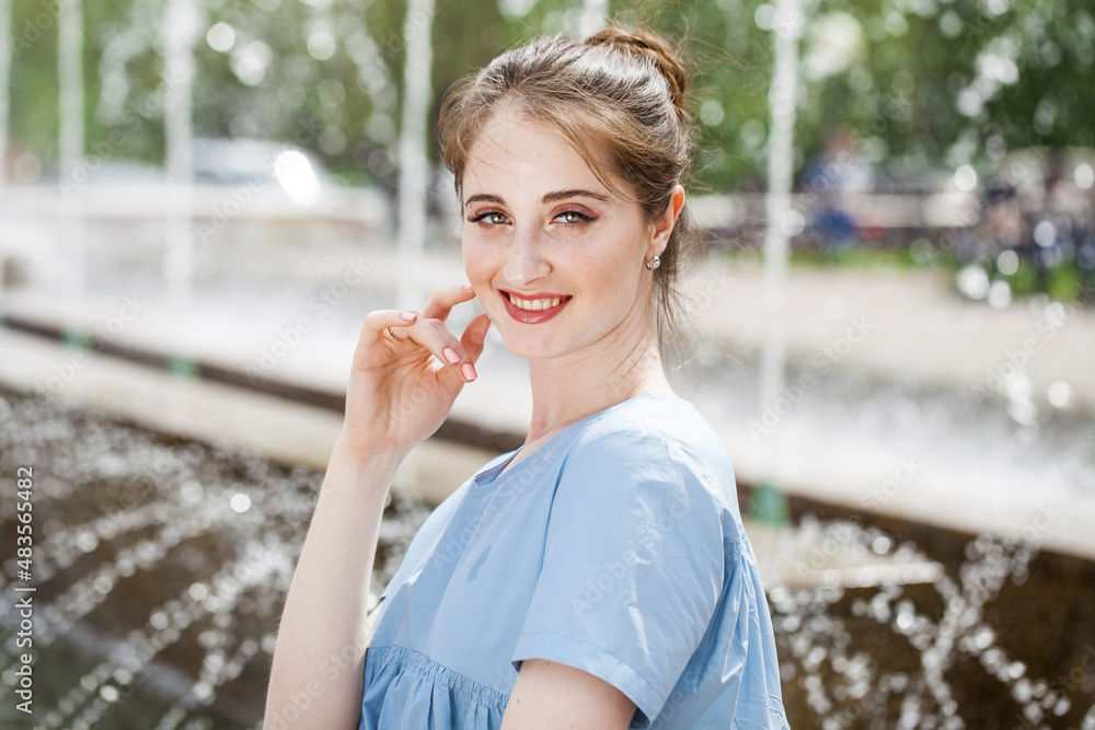 Fototapeta premium Young beautiful woman in a luxurious turquoise dress posing on the street