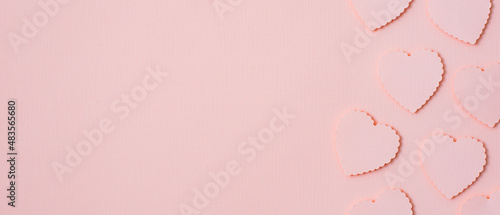 Paper elements in shape of heart flying on pink paper background. © shangarey