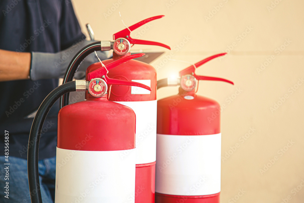 Naklejka premium Close up fire extinguisher and firefighter checking in the back for protection and prevent and safety rescue and use of equipment on fire training concept.