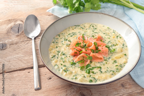 Homemade vegetarian cream soup from parsley leaves and potatoes with strips of smoked salmon on a rustic wooden table, copy space, selected focus