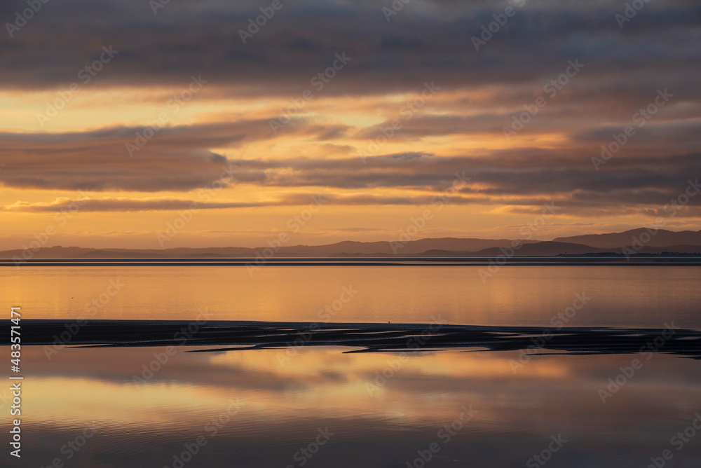 Beautiful sunset landscape image of Solway Firth viewed from Silloth during stunning Autumn sunset with dramatic sky and cloud formations