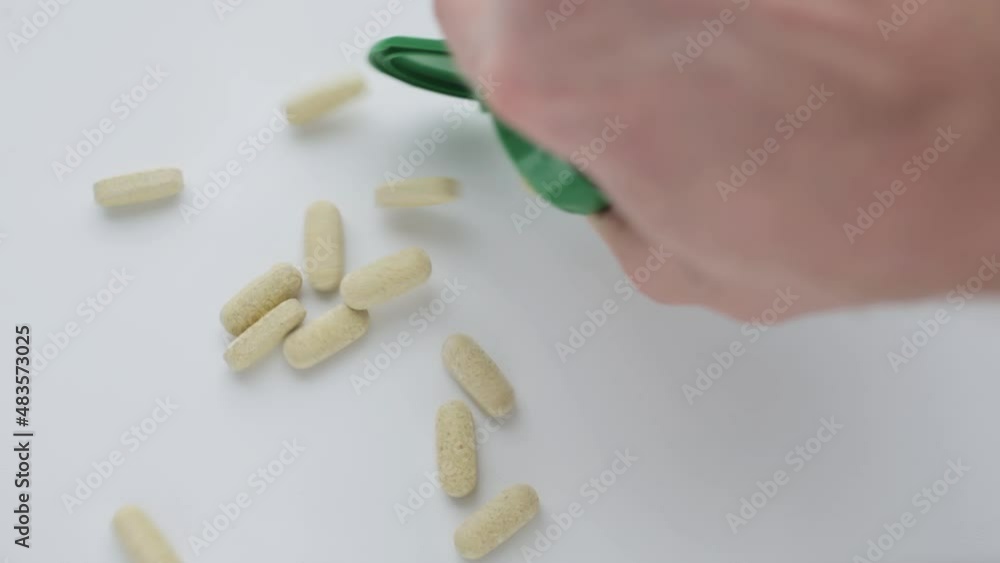 Herbal vitamins pills are dropped from green bottle. Herbal vitamins pills are dropped from green bottle.