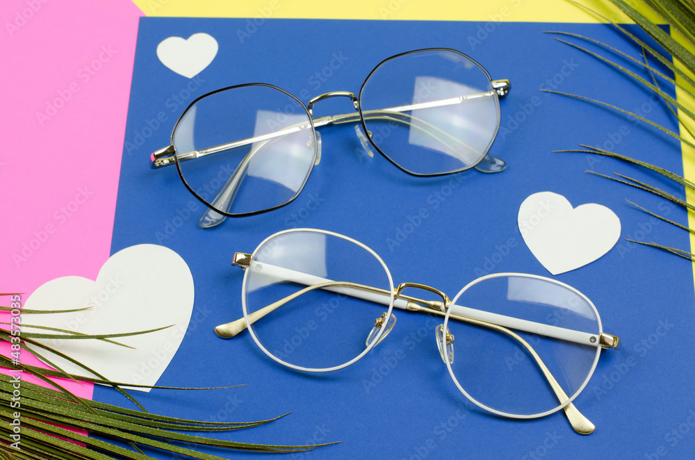 Stylish glasses on a colored background with palm leaves and white hearts. Glasses set, selective focus