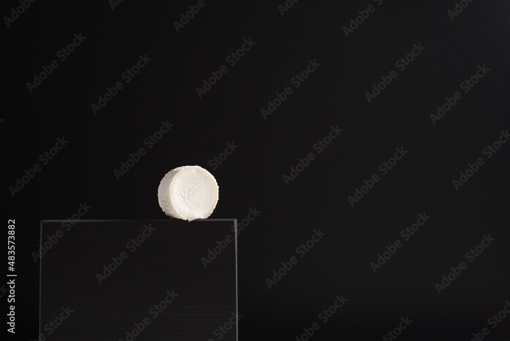 Queso cremoso de cabra sobre piedra negra y fondo negro. Concepto minimalista Queso cremoso de cabra sobre piedra negra y fondo negro. Concepto minimalista