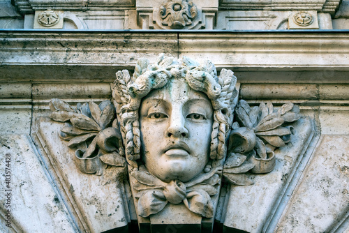 Photography Close-up of a stone human face as decor or Mascaron on building facade