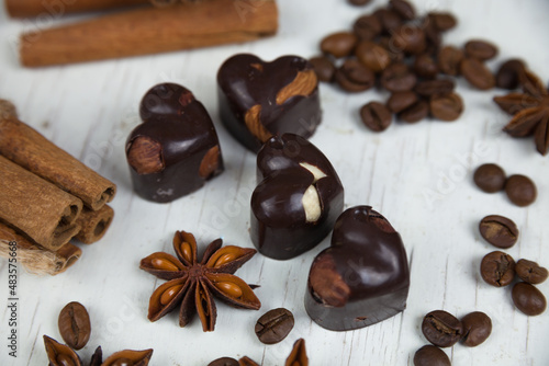 Chocolate candies, anise stars with cinnamon sticks and coffee beans on a white wooden background. Country style. 