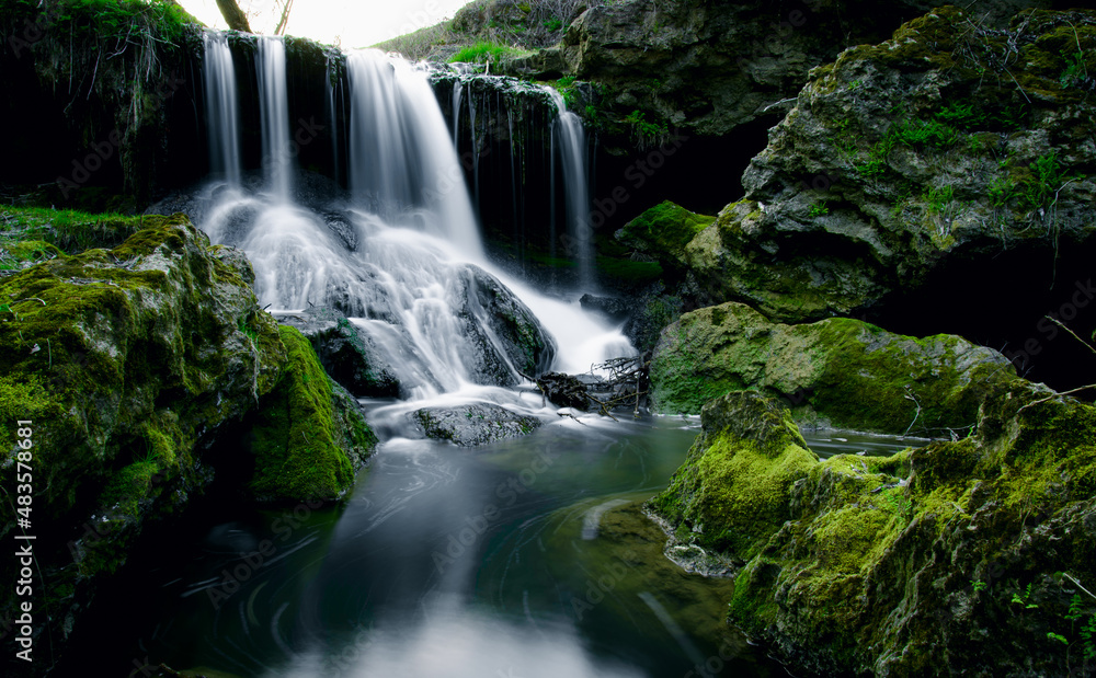 Fototapeta premium waterfall in the forestagainst the background of green moss and rocks