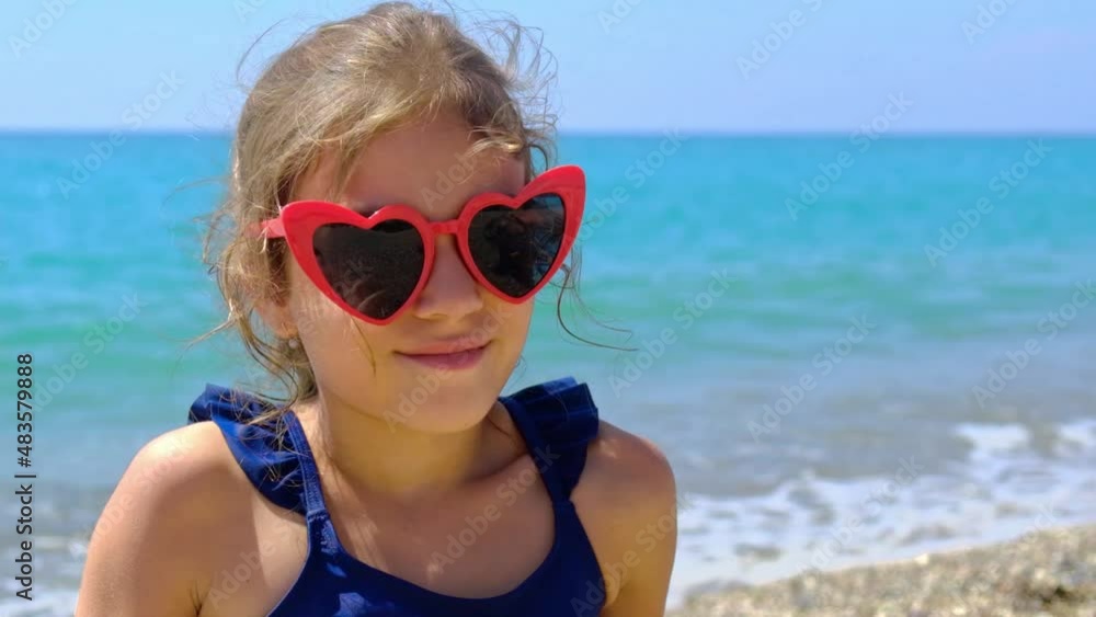 A child is sunbathing on the beach in sunglasses. Selective focus. A child is sunbathing on the beach in sunglasses. Selective focus.