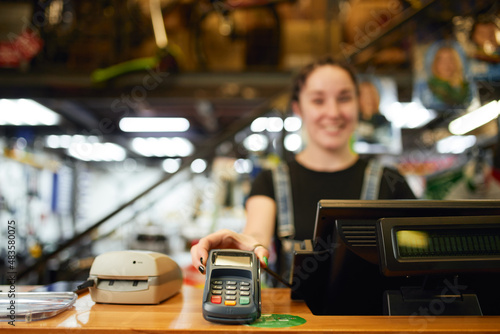 Fotografie Positive woman giving payment terminal in shop