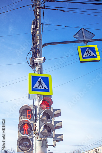 Traffic light with a surveillance camera against a blue sky with white clouds photo