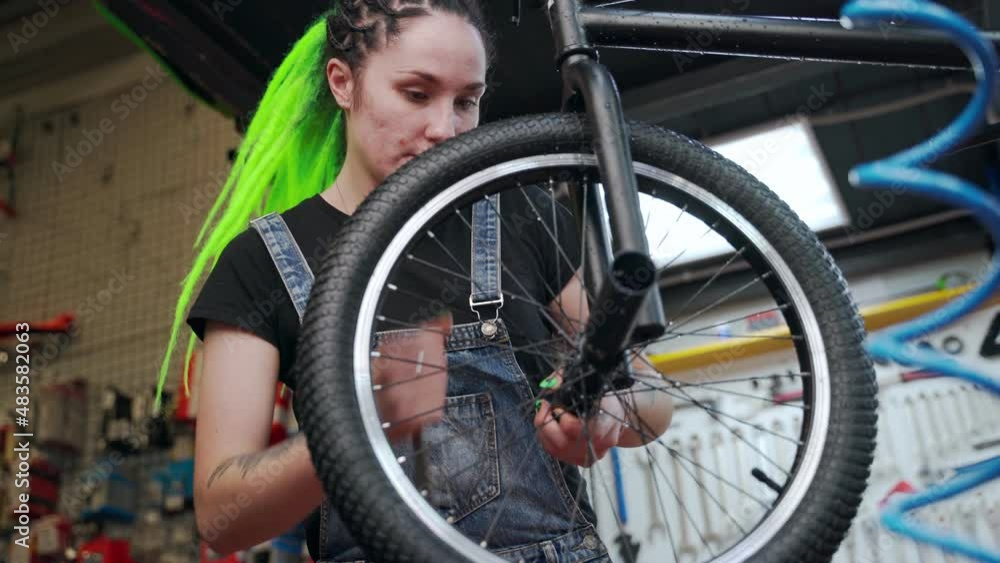 Alternative woman repairing bicycle in workshop Alternative woman repairing bicycle in workshop