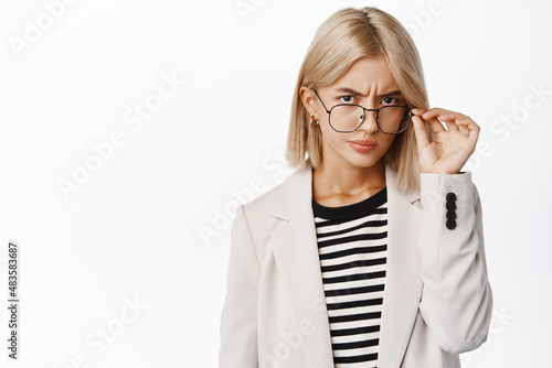 Bild auf Leinwand Suspicious young woman looking under glasses, squinting and staring doubtful, ha
