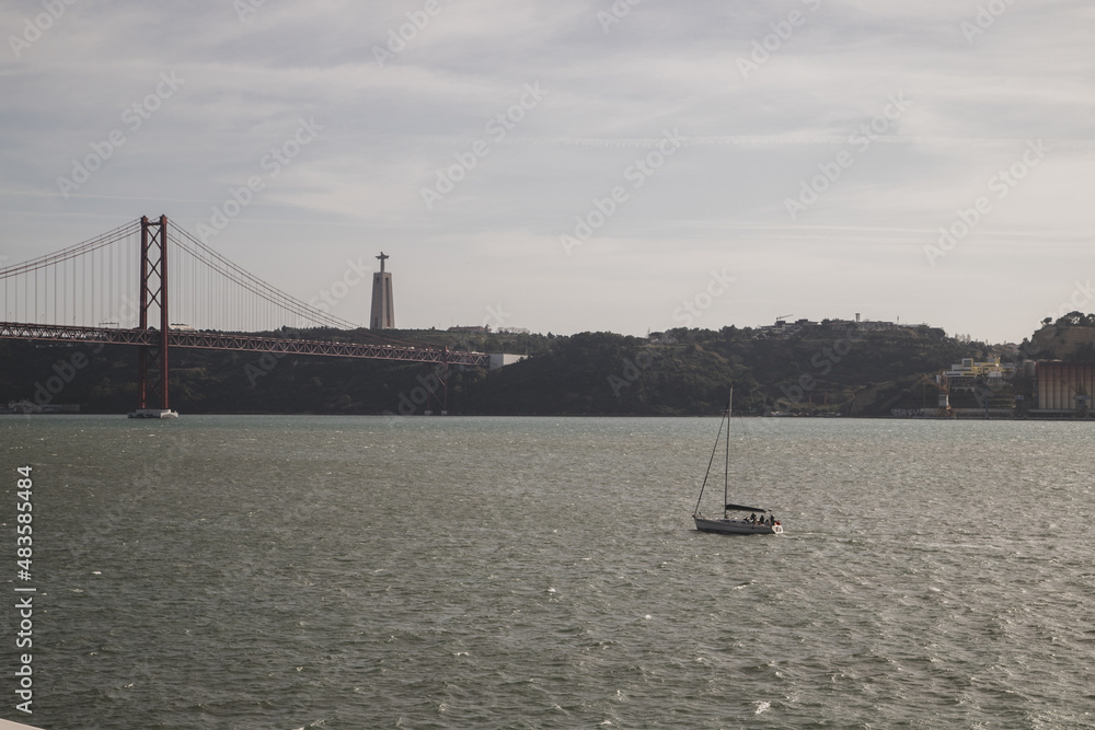 25 April Bridge and Sailing boat in Tejo river at Lisbon