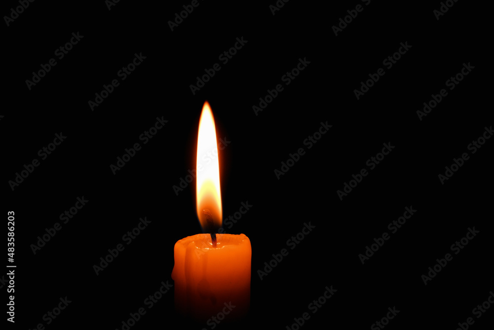 Candle flame on black background. Single lit candle with quite flame. Dramatic burning candle flame on a black background with copy space Candle flame on black background. Single lit candle with quite flame. Dramatic burning candle flame on a black background with copy space