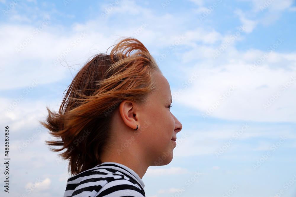profile of a smiling red-haired teenage girl against a cloudy sky profile of a smiling red-haired teenage girl against a cloudy sky