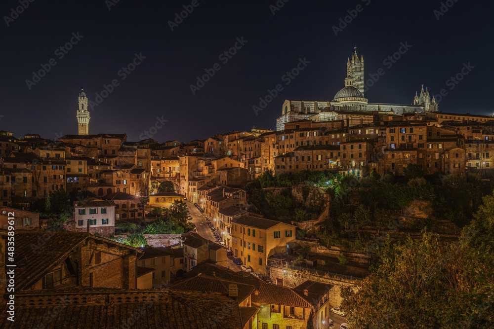 Amazing night cityscape with two iconic landmarks: Torre del Mangia on the right and the Cathedral of Siena on the left, Tuscany, Italy