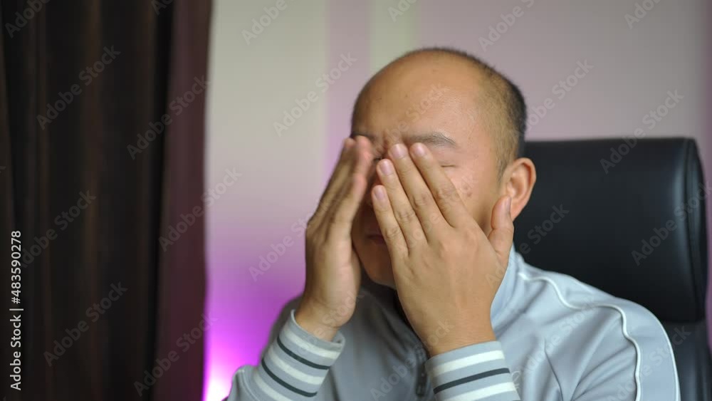 Asian Male is massage his eyes due tiredness. Asian Male is massage his eyes due tiredness.