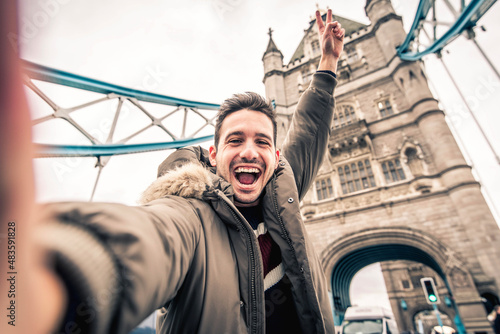 Smiling man taking selfie portrait during travel in London  England - Young tourist male taking holiday pic with iconic england landmark - Happy people wandering around Europe concept