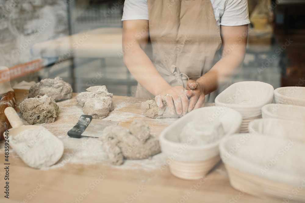A woman baker kneads the dough and puts it in a wooden form. Bakery concept. A woman baker kneads the dough and puts it in a wooden form. Bakery concept.