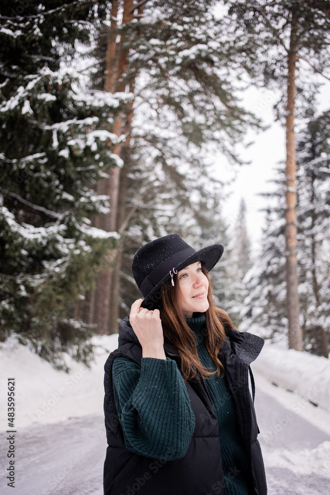 Caucasian young woman in black hat in winter snowy forest. Caucasian young woman in black hat in winter snowy forest.