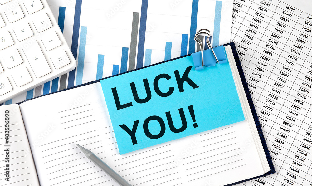 LUCK YOU text on blue sticker on the chart background near calculator LUCK YOU text on blue sticker on the chart background near calculator