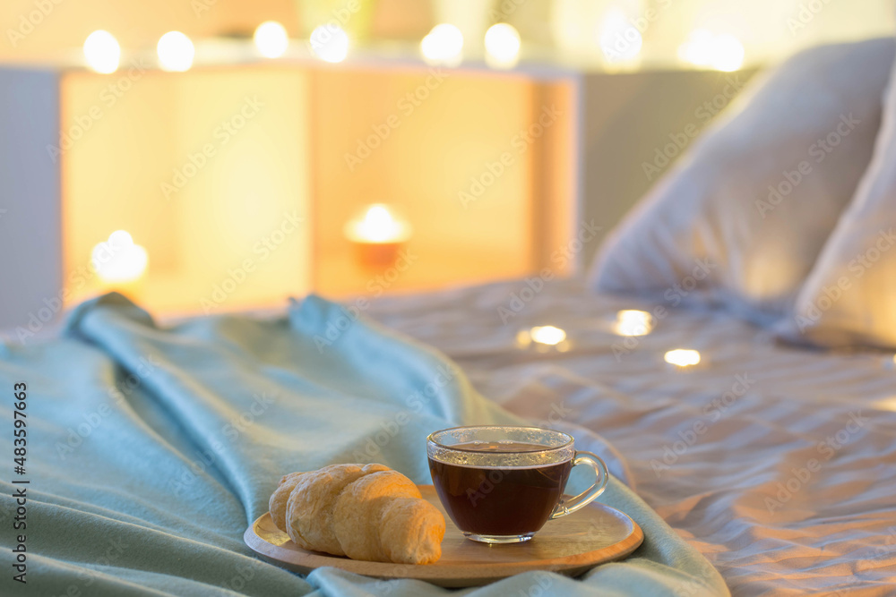 cup of coffee with croissant   on bed in  evening