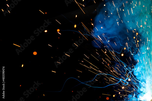 Close up view and background of the gas metal arc welding (GMAW) process with sparks, light, bokeh effect and smoke.