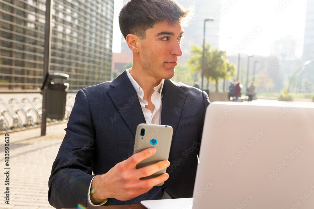 Young entrepreneur using the mobile while working on his laptop in a cafe. Trading on mobile. Young entrepreneur using the mobile while working on his laptop in a cafe. Trading on mobile.