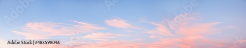 wide sky panorama with fluffy light pink cirrus clouds at sunset
