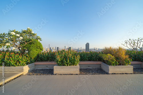 Sky garden on private rooftop of condominium or hotel, high rise architecture building with tree, grass field, and blue sky.