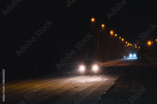 Cars in a snowstorm at night on the road in winter. Traffic in winter. Defocused
