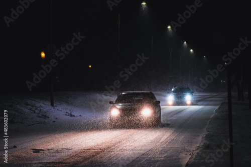 Cars in a snowstorm at night on the road in winter. Traffic in winter. Defocused